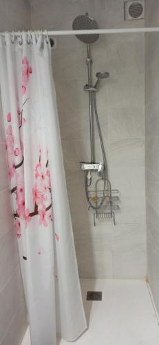 um chuveiro com uma cortina de chuveiro branca com flores cor-de-rosa em Maison au calme em Viry