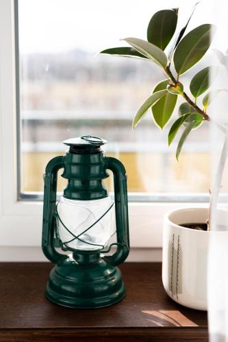 a green lantern sitting on a table next to a plant at Firpo Apartman in Eger