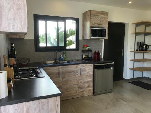 a kitchen with a sink and a stove and a window at Villalina : Cosy, piscine privée, proche Grand Baie et plages in Pereybere