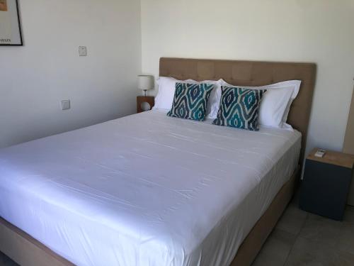 a bedroom with a large white bed with blue pillows at Villalina : Cosy, piscine privée, proche Grand Baie et plages in Pereybere