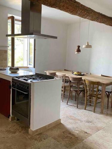 une cuisine avec une cuisinière et une table avec des chaises dans l'établissement “La belle vie” en Provence, à Malemort-du-Comtat
