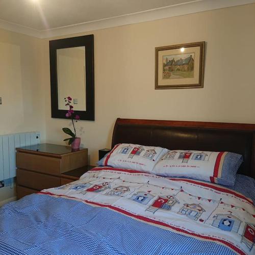 een slaapkamer met een bed, een dressoir en een spiegel bij Stylish 2 bed flat at Camber Sands in Camber