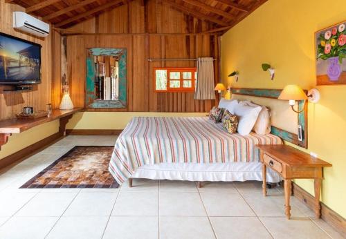 1 dormitorio con cama, mesa y TV en Pousada Casa do Ceo, en Praia do Rosa