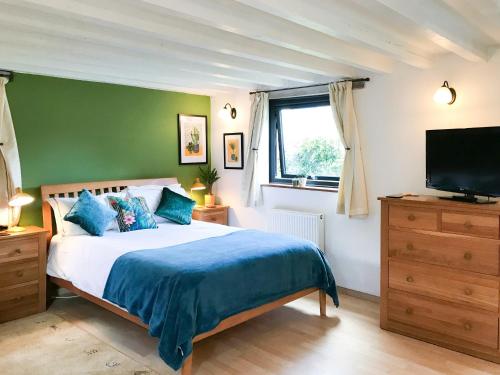 a bedroom with a bed and a flat screen tv at Little Fursdon Apartment in Merrymeet