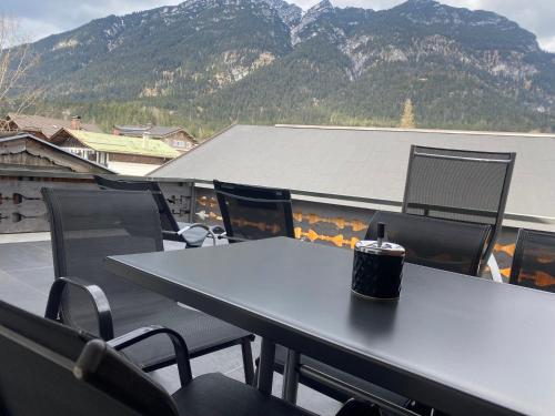 stół i krzesła na balkonie z górami w tle w obiekcie Ferienhaus Butterfly w Garmisch Partenkirchen