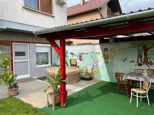 a patio with a table and a wall with a mural at Kata apartment in Tolna