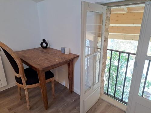 una mesa de madera y una silla en una habitación con ventana en Hôtel restaurant Clos des Sullys, en Montclus
