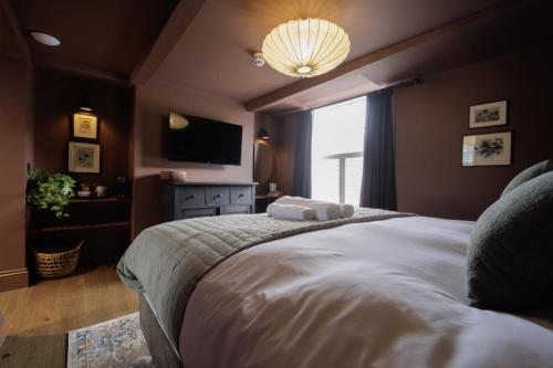 a bedroom with a large bed and a television at The Silk Rooms, at The Freemasons Inn in Knutsford