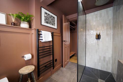 a bathroom with a glass shower and a stool at The Silk Rooms, at The Freemasons Inn in Knutsford