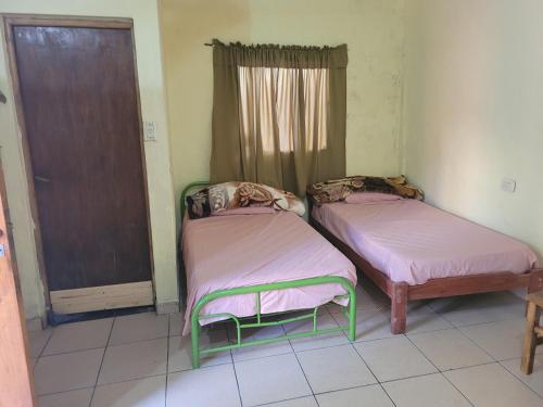 Duas camas num quarto com uma janela em Lautaro alojamiento em Posadas