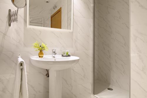 une salle de bain blanche avec un lavabo et un miroir dans l'établissement Muinoa 2 by FeelFree Rentals, à Saint-Sébastien