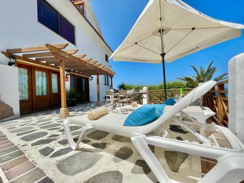 eine Terrasse mit einem Stuhl und einem Sonnenschirm in der Unterkunft Bollullo Paradise in La Orotava