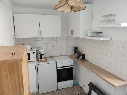 - une cuisine avec des appareils électroménagers blancs et du carrelage blanc dans l'établissement location appartement 100 m de la plage, à Pénestin