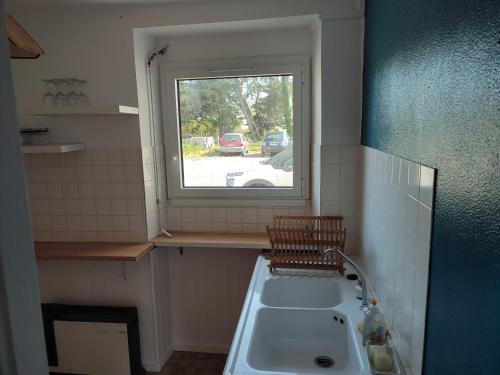uma casa de banho com um lavatório e uma janela em location appartement 100 m de la plage em Pénestin