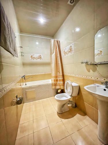 a bathroom with a toilet and a sink and a tub at Nurafshon Boutique in Bukhara