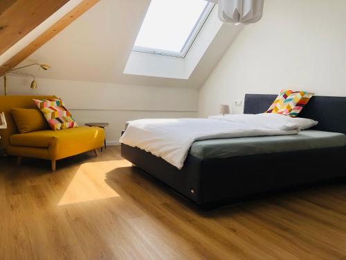 a bedroom with a bed and a yellow chair at Wohnen auf Zeit - Dachgeschosswohnung mit Bergblick in Bruckmühl