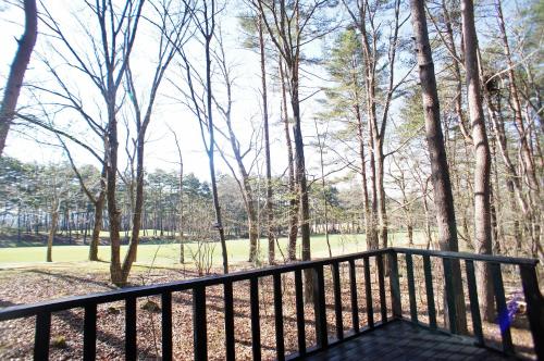 a balcony with a view of the woods at HARUNA WING Private cottage in the forest overlooking the golf course in Tsumagoi