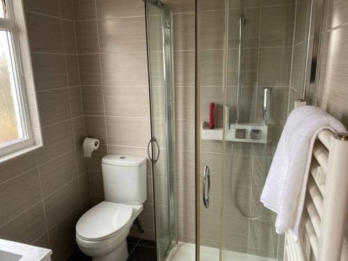 a bathroom with a toilet and a glass shower at Amazing 4 bed Contractor hub in Nuneaton