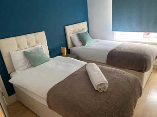 Amazing 4 bed Contractor hub في نيونياتون: سريرين في غرفة بجدران زرقاء