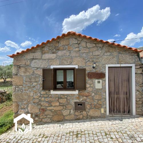 a stone house with a window and a door at A casa da avó Mina in Sortelha
