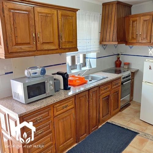 a kitchen with wooden cabinets and a microwave at A casa da avó Mina in Sortelha