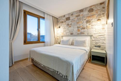 1 dormitorio con 1 cama grande y pared de piedra en Hanedan Hotel Foca Izmir, en Foca