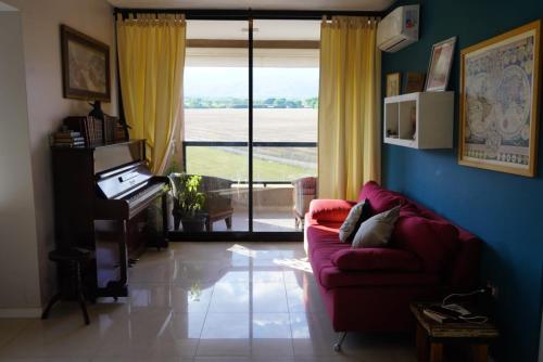 een woonkamer met een rode bank en een piano bij Departamento 1 dormitorio, complejo Buena Vista in Yerba Buena