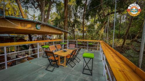 a wooden table and chairs on a deck with trees at Kaabo Hostel in Vagator