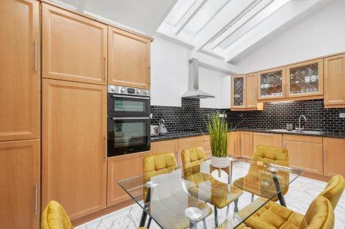 uma cozinha com uma mesa de vidro e cadeiras amarelas em Hububb Luxury Knightsbridge House em Londres