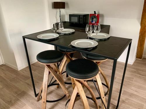 un tavolo nero con quattro sedie e bicchieri da vino di Appartement cosy vue sur le vignoble a Sancerre