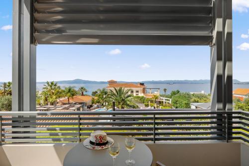 a table with two glasses of wine and a view of the ocean at Akti Taygetos - Conference Resort in Kalamata