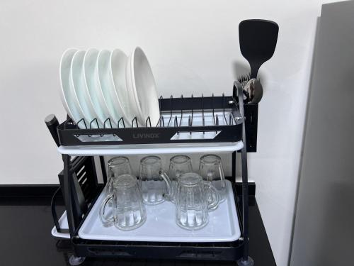 a dish rack with plates and glasses on it at METROPOL SERVICED APARTMENT at Bukit Mertajam, Pulau Pinang in Bukit Mertajam