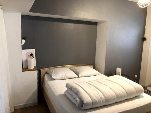 a bedroom with a white bed with a gray wall at T2 meublé pour curistes, vacanciers et stagiaires in Rochefort