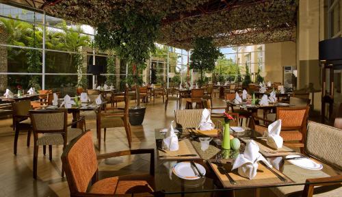 a dining room with tables and chairs and windows at Novotel Semarang in Semarang