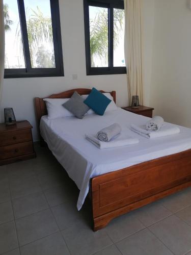a bedroom with a large bed with two windows at Villa Med-Sunset in Kissonerga