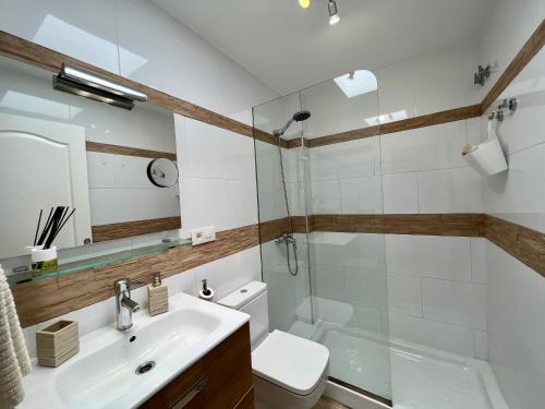 ein Badezimmer mit Waschbecken, Toilette und Dusche in der Unterkunft Beach Cottage in Maspalomas