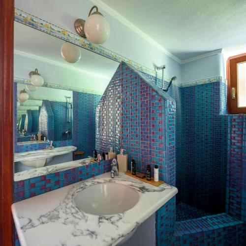 a blue tiled bathroom with a sink and a mirror at Aquaria Villa in Karterados