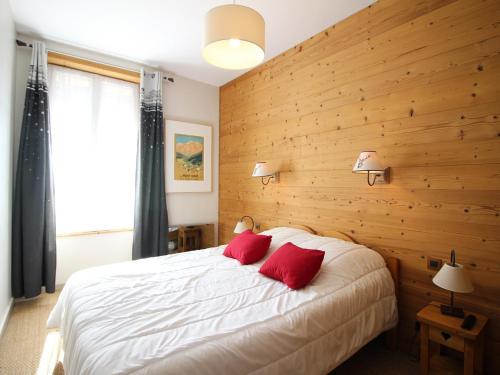 une chambre avec un grand lit blanc avec des oreillers rouges dans l'établissement T2 Bis Charmant au Mont-Dore avec Animaux Acceptés - FR-1-608-182, à Le Mont-Dore