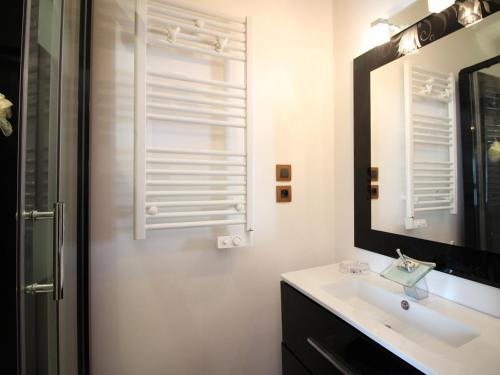 une salle de bain blanche avec un lavabo et un miroir dans l'établissement T2 Bis Charmant au Mont-Dore avec Animaux Acceptés - FR-1-608-182, à Le Mont-Dore