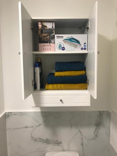 a white cabinet with towels in a bathroom at Studio Moderne au Victor Hugo in Les Mureaux