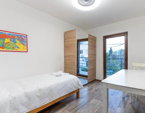 a white bedroom with a bed and a table at Casa Bella in Karlobag