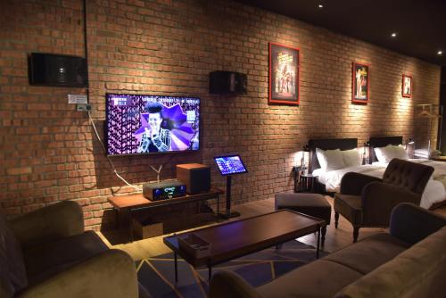 a living room with a couch and a bed and a tv at The Label Suites Ipoh in Ipoh