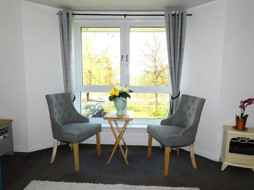 a living room with a table and two chairs and a window at Fab Location 1 bed Apt overlooking Glasgow Green in Glasgow