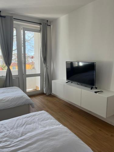 ドレスデンにあるMonteur-& Ferienwohnung Eichmannの白いキャビネット(薄型テレビ付)が備わる白いベッドルームです。