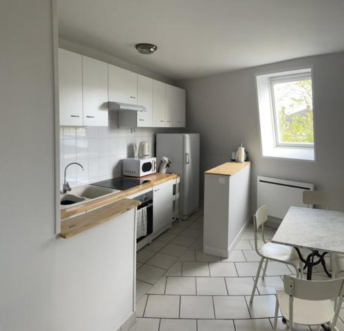 une cuisine avec des appareils blancs et une table avec des chaises dans l'établissement Le Céleste, à Épernay