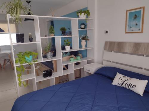 1 dormitorio con cama azul y estanterías con macetas en Apartamento Costa del Sol en Mar del Plata