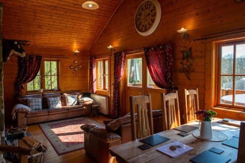 - un salon dans une cabane en rondins avec une table dans l'établissement George Cabin - Log Cabin in Wales with Hot tub, à Newtown