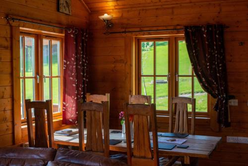 - une salle à manger avec une table, des chaises et des fenêtres dans l'établissement George Cabin - Log Cabin in Wales with Hot tub, à Newtown