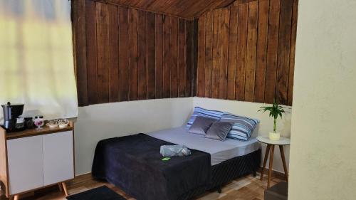 a small bed in a room with a wooden wall at Chalé Recanto da Cachoeira I in Eldorado
