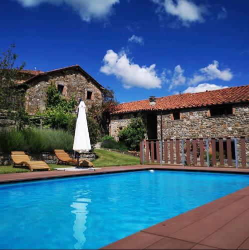 a swimming pool with a umbrella next to a building at Agriturismo Cilla in Giuncugnano
